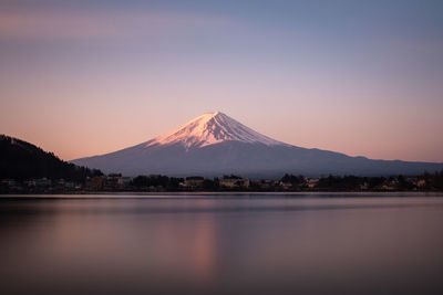 Scenic view of lake by mountains against sky during sunset