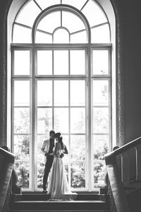 Rear view of man standing in front of window