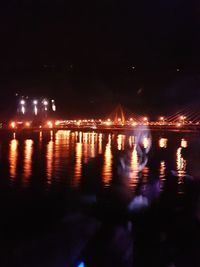 Illuminated bridge over river against sky at night