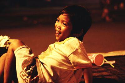 Smiling boy looking away while sitting on ground