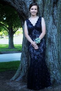 Portrait of smiling young woman standing by tree trunk