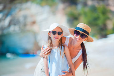 Portrait of mother and daughter wearing hat on beach