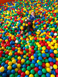 Full length of boy playing with multi colored balloons