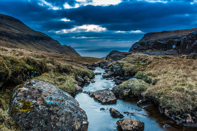 A narrow water channel in the mountain field against a cloudy sky. high quality photo