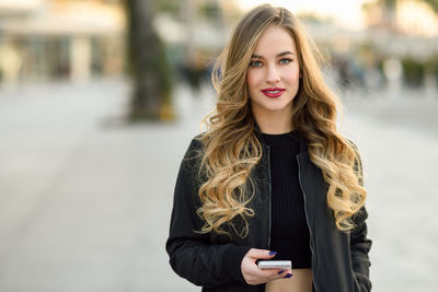 Portrait of beautiful young woman standing in city