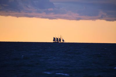 Sailboat sailing on sea against sky during sunset