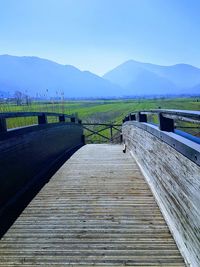 Boardwalk leading towards mountain against sky