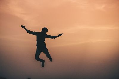 Silhouette man jumping against sky during sunset