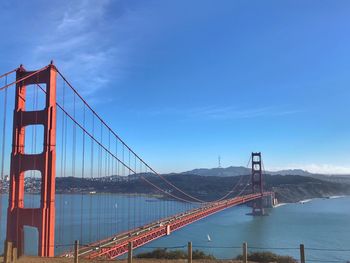 Suspension bridge over river against cloudy sky