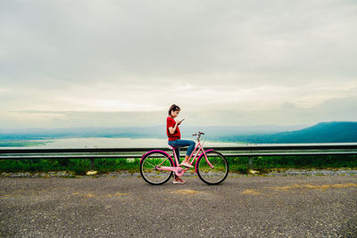 Man riding bicycle on road against sky