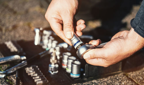 Cropped hands of mechanic holding vehicle part