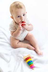 Cute girl playing with toy blocks on bed at home