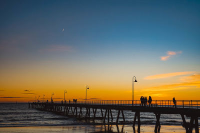 Silhouette pier on beach against sky during sunset