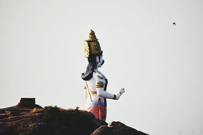 Low angle view of statue against building against clear sky