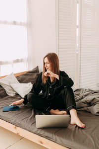 Young woman using phone while sitting on table