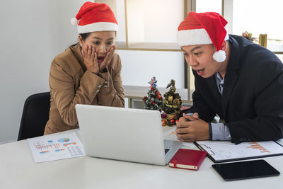 Shocked businessman and colleague sitting at desk in office