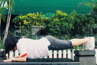 Side view of woman exercising in plank position against plants