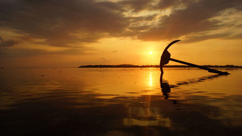 Anchor in sea against cloudy sky during sunset