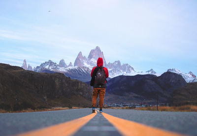 Rear view of woman walking on road against mountain