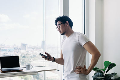 Young man using mobile phone while standing on table