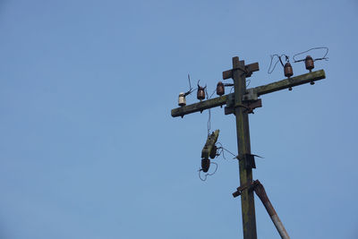 Low angle view of abandoned electricity pylon against clear blue sky