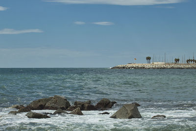 Seascape with rocks in the foreground and breakwater in the background