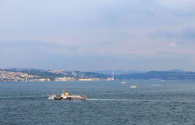 Sailboat sailing on sea against sky in city