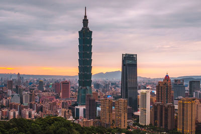 Modern buildings in city against sky during sunset