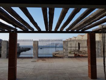 Low angle view of bridge against sky seen through fence