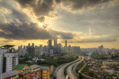 Cityscape against cloudy sky at sunset