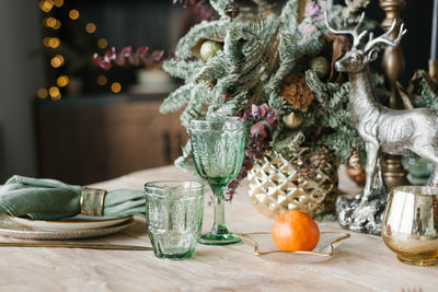 Festive christmas dinner setting. green wine glasses, branches of fir or spruce in a vase, plates