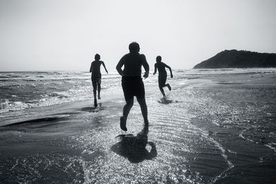 Boys running on shore during sunny day