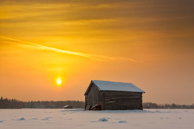 Old barn on landscape against sky during sunset