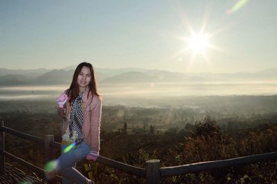 Portrait of young woman standing on landscape