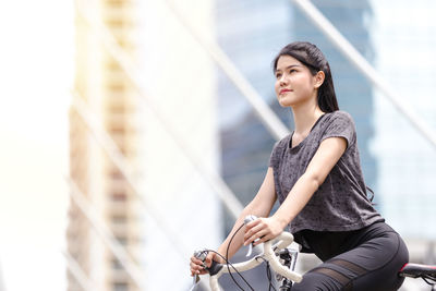 Young woman riding bicycle on railing