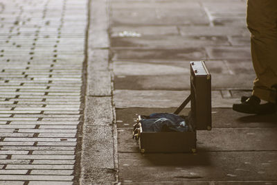 Low section of man standing by open box on footpath in city