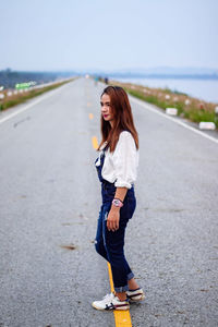 Thoughtful young woman looking away while standing on road