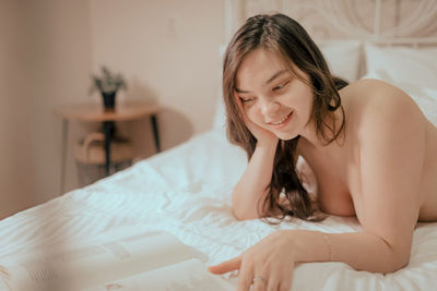 Young woman sitting on bed at home