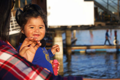 Cropped image of baby girl with mother by sea