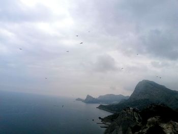 Scenic view of sea and mountains against sky