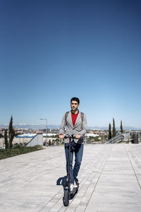 Portrait of man riding bicycle against clear sky