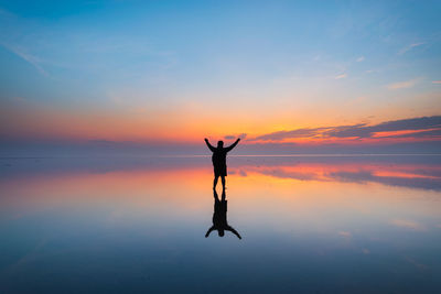 Silhouette man standing on beach against sky during sunrise, infinity beach thai binh