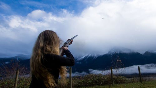 Rear view of woman photographing against sky