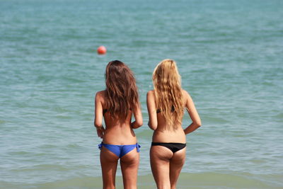 Rear view of friends standing in sea