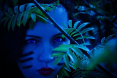 Close-up of woman with face paint by plant