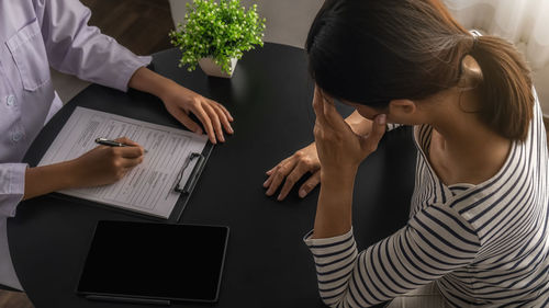 Woman using phone while sitting on table