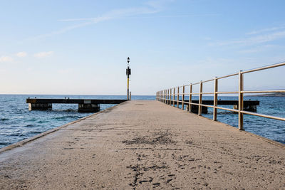 Pier on beach against sky