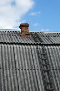 Low angle view of old house roof against sky