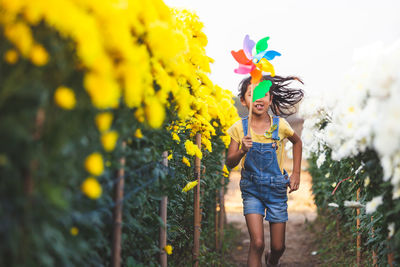 Girl running with pinwheel toy amidst flowering plants