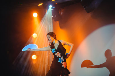 Woman holding illuminated lighting equipment at night